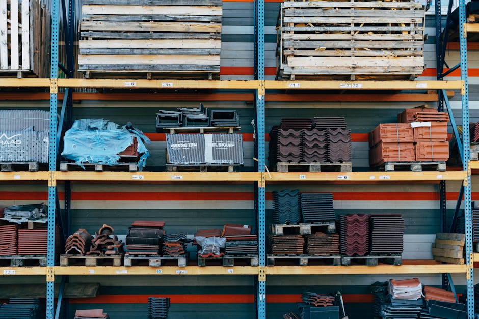 Shelves filled with construction materials like tiles and wood pallets in a warehouse setting.